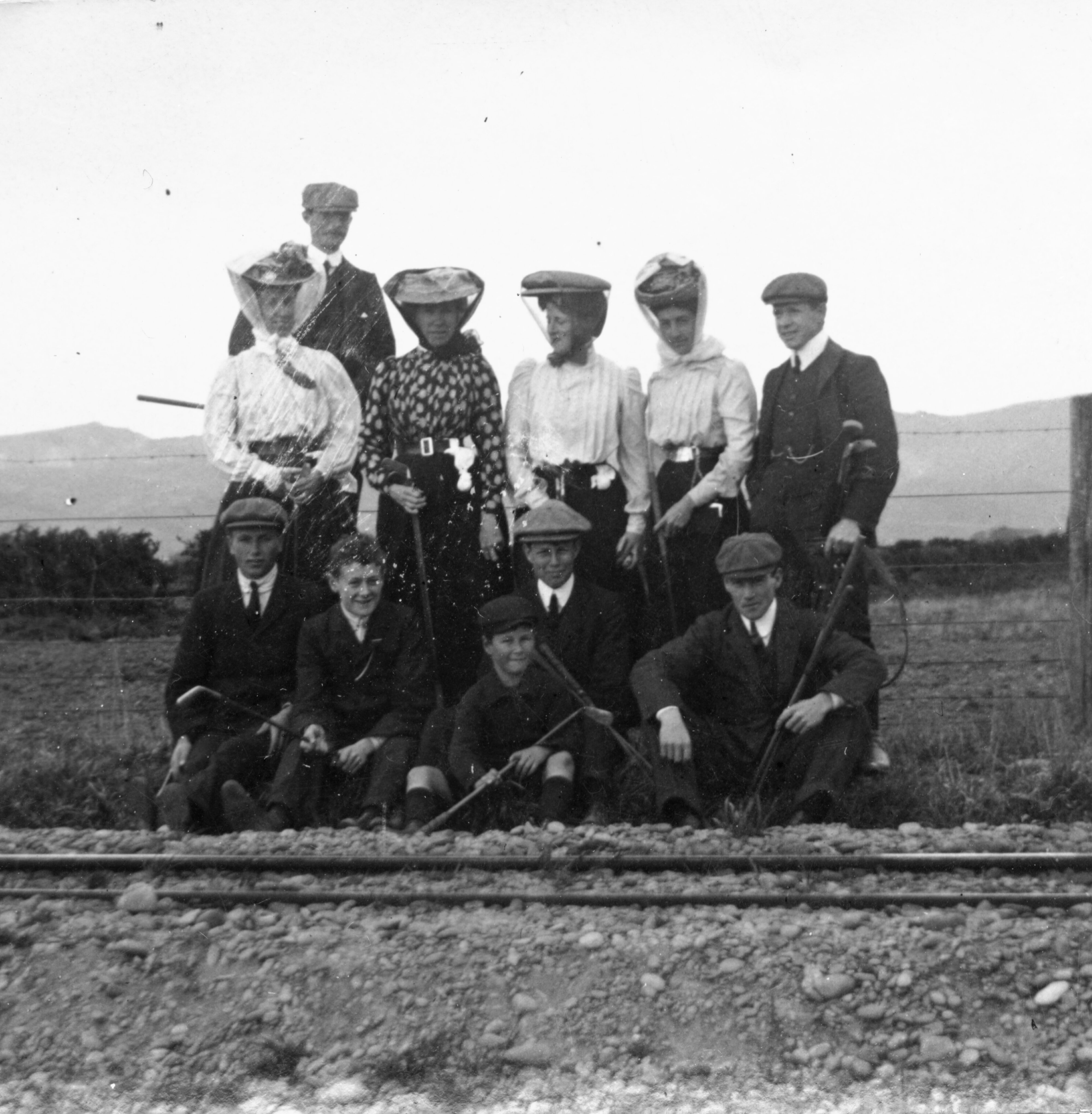 People standing by the Little River railway line, some with golf clubs.