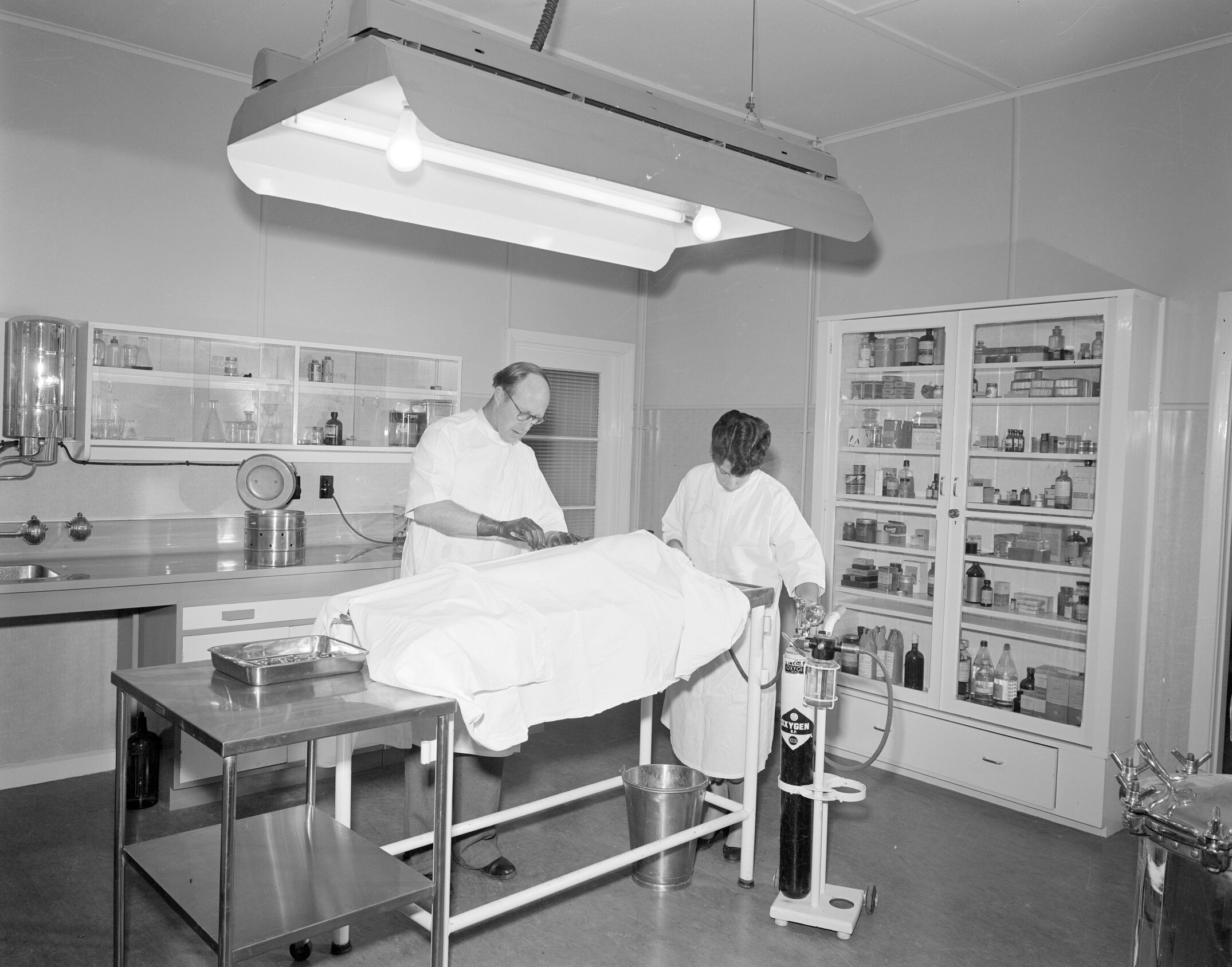 G.G.Thompson uses the operating theatre in the new veterinary block,1957 (Blackmore Neg 5175)