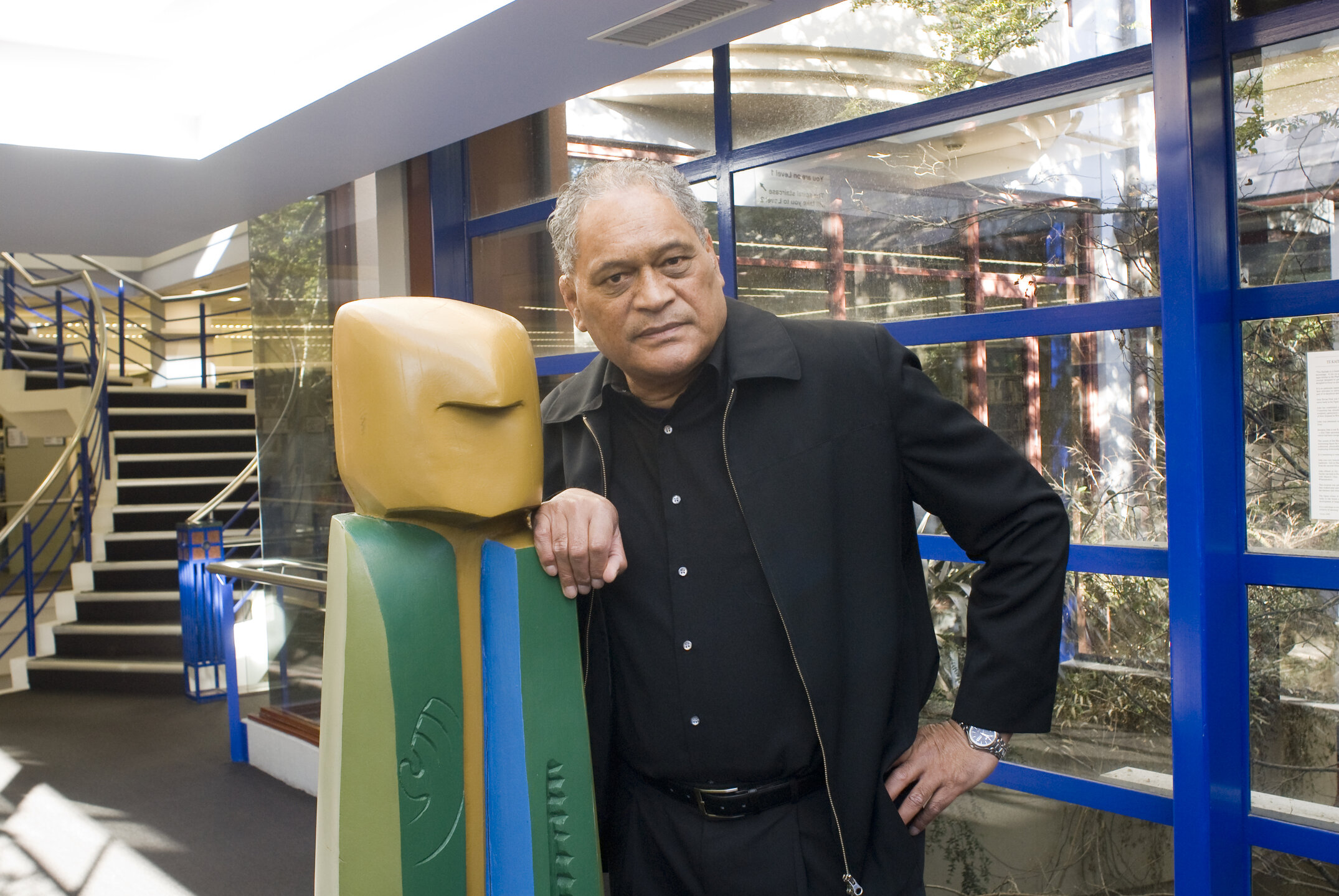 Ekara Lewis standing next to the Kaitiaki Figure in Ivey hall
