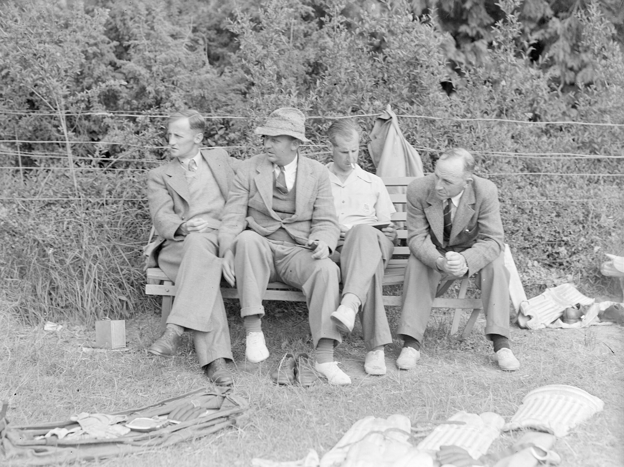 G.B. McLeod, P.G. Stevens and  I.D. Blair seated on bench beside cricket equipment (Blackmore Neg 5917)