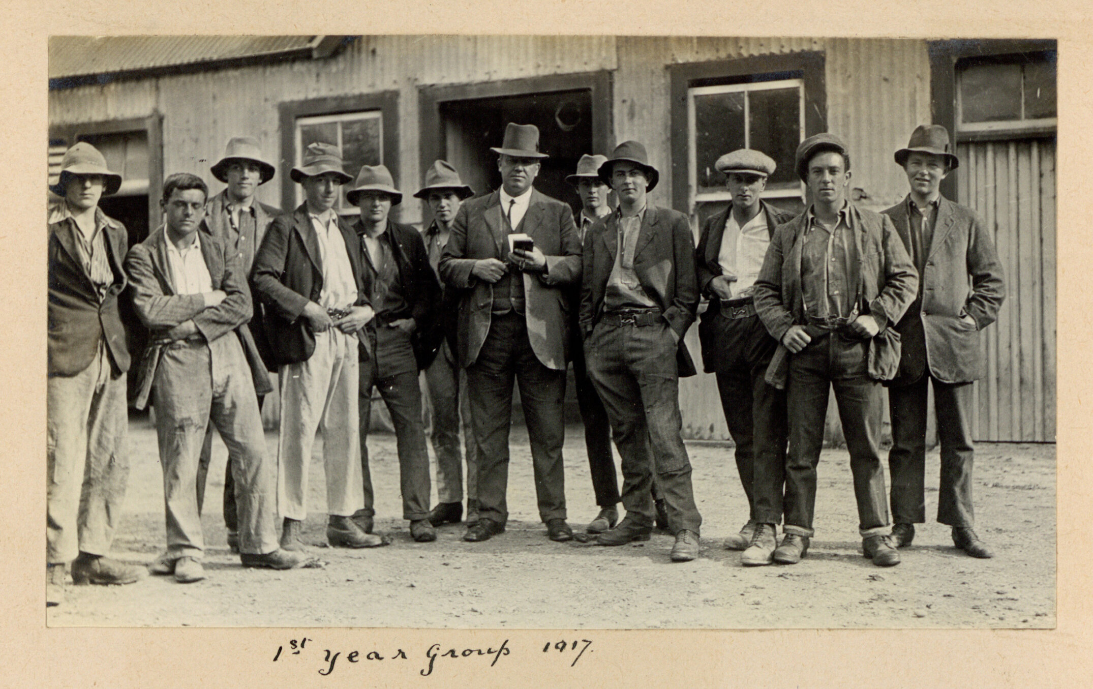 Canterbury Agricultural College 1st year student group and farm manager G. A. Willis in front of a College farm building, 1st year group 1917