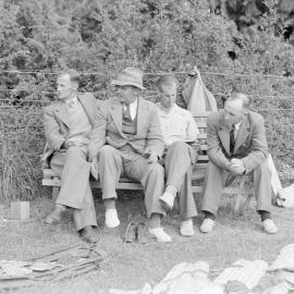 G.B. McLeod, P.G. Stevens and  I.D. Blair seated on bench beside cricket equipment (Blackmore Neg 5917)