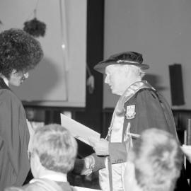 Sidney M. Hurst, Chairman of the College Council Presenting a Degree Certificate at Graduation Ceremony, 1985 06
