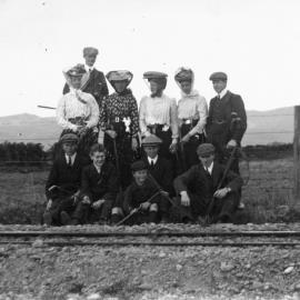 People standing by the Little River railway line, some with golf clubs.